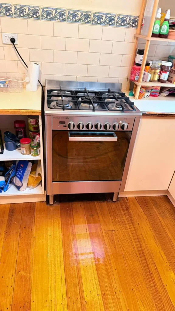 Residential kitchen cleaning with restored timber flooring and cleaned cooking area.